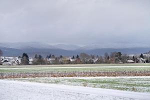 a snowy field with a road and mountains in the background at Haus Ruth in Hörden