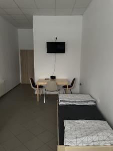 a room with two beds and a table and a tv at Noclegi Pracownicze LAZUR in Ciechanów