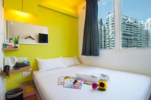 a bedroom with a bed with a yellow wall and a window at Fragrance Hotel - Classic in Singapore