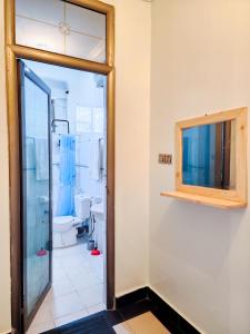 a bathroom with a toilet and a glass door at Fefe's home in Dar es Salaam