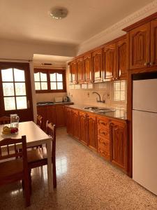 a kitchen with wooden cabinets and a table and a refrigerator at Ten minutes from airport in Vecindario