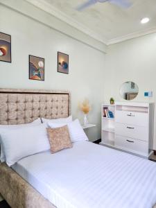 a bedroom with a large white bed and a dresser at Fefe's home in Dar es Salaam