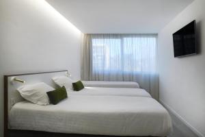 2 camas en una habitación de hotel con ventana en Hotel-Restaurant Isidore Nice Ouest, en Niza