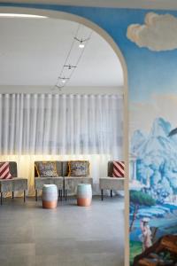 un salon avec des canapés et un mur orné d'une fresque murale. dans l'établissement Hotel-Restaurant Isidore Nice Ouest, à Nice