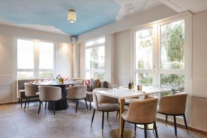 a restaurant with tables and chairs and windows at Hotel Restaurant Isidore by Soniho in Nice