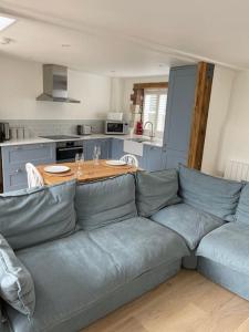 uma sala de estar com um sofá azul e uma cozinha em The Stable at Thornlea em Axminster