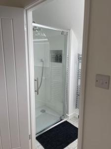 uma casa de banho com um chuveiro e uma porta de vidro em The Stable at Thornlea em Axminster