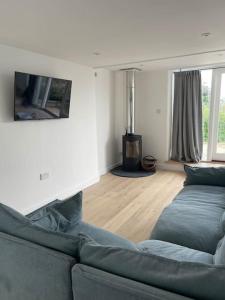 uma sala de estar com um sofá azul e uma televisão em The Stable at Thornlea em Axminster