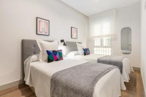a white bedroom with two beds and two windows at Apartamento para 4 en Chamberi Quevedo V in Madrid