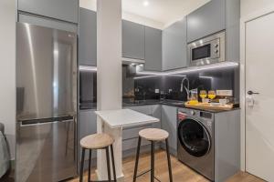 uma cozinha com uma máquina de lavar roupa e 2 bancos em Apartamento para 2 en Chamberi Quevedo IV em Madrid