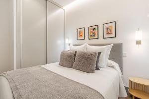 um quarto branco com uma grande cama branca com almofadas em Apartamento para 2 en Chamberi Quevedo IV em Madrid