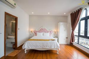 a bedroom with a white bed with a pink headboard at Hoàng Gia Hotel Tuy Hoà in Tuy Hoa