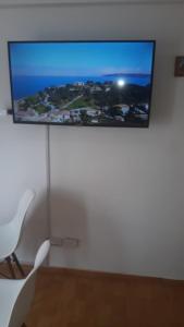 a flat screen tv on a white wall with a chair at alquiler temporario en Córdoba Capital, excelente ubicación in Cordoba