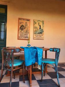 un tavolo con sedie blu e poster appesi al muro di Casa Vidal Guesthouse a Tupungato