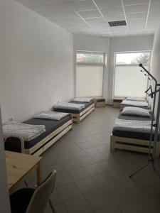 a room with three beds and a table and two windows at Noclegi Pracownicze LAZUR in Ciechanów