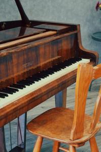 ein Holzklavier und ein Holzstuhl daneben in der Unterkunft Khaz Cottage Dilijan in Dilidschan