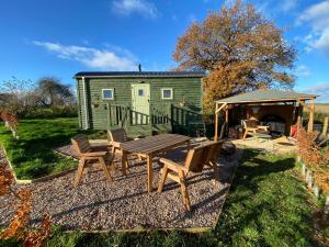 un patio trasero con mesa de picnic y cenador en Spring Grounds Farm Shepherd Huts 