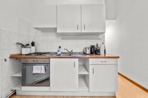 a white kitchen with a sink and a stove at primeflats - Apartment Leberstr 58 Berlin Schöneberg in Berlin