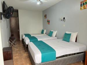 3 camas en una habitación de color azul y blanco en Hotel Redinson, en Piura