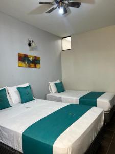 2 łóżka w pokoju z wentylatorem sufitowym w obiekcie Hotel Redinson w mieście Piura