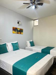 2 camas en una habitación con ventilador de techo en Hotel Redinson, en Piura