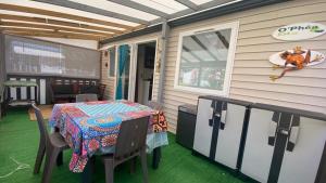 une terrasse couverte avec une table et des chaises. dans l'établissement Mobil home (Clim, Lv, Ll)- Camping Vic-la-Gardiole 4* - 012, à Vic-la-Gardiole