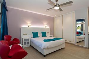 a bedroom with a bed and a red chair at Apartamentos Panorama Adults Only in Puerto del Carmen