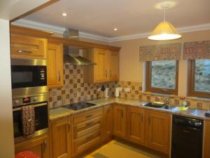 a kitchen with wooden cabinets and a stove top oven at Hill Cottage in Kensaleyre