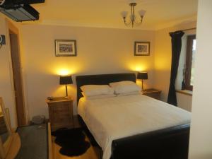 ein Schlafzimmer mit einem Bett mit zwei Lampen und zwei Tischen in der Unterkunft Hill Cottage in Kensaleyre