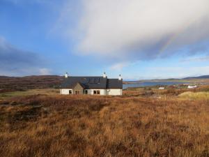 a house on a hill with a rainbow in the sky at Hill Cottage in Kensaleyre