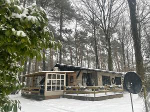 una casa nel bosco con la neve sul terreno di Chalet Sint-Hubertus Deluxe a Zutendaal