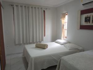 a white bedroom with two beds and a window at Aconchegante casa de Temporada em Búzios. in Armacao dos Buzios