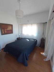 a bedroom with a black bed in a room with a window at Departamento frente al mar 3 ambientes Playas de Surf in Mar del Plata