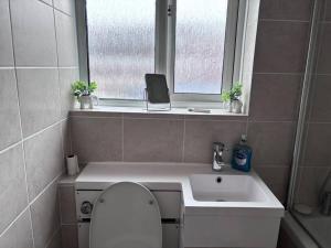 a bathroom with a toilet and a sink and a window at Cosy Spacious 2 bed flat Hornchurch high street in Hornchurch