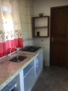 a kitchen with a sink and a stove and a mirror at Guaraflat in Guaratuba