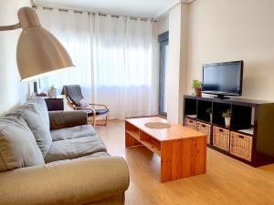 ein Wohnzimmer mit einem Sofa und einem TV in der Unterkunft CT28 Relax by the beach (free parking and pool) in Málaga