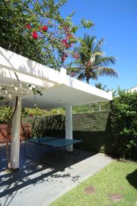 a white umbrella with a table under it at Casa em Jardim Acapulco-Guarujá in Guarujá