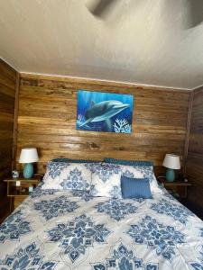 1 dormitorio con 1 cama con 2 lámparas y una pintura en la pared en Ponci’s Gate to Gaia Holistic Center en Bocas Town