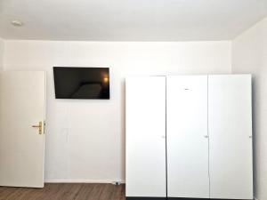 Cette chambre dispose d'armoires blanches et d'une télévision murale. dans l'établissement Meribu L92 Wohnung für Monteure und Arbeiter, à Essen