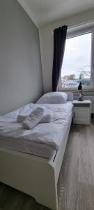 ein großes weißes Bett in einem Zimmer mit Fenster in der Unterkunft Zweibettzimmer "Grau" in zentraler Lage in Bremen