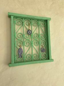 a green metal window on a wall with earrings at Dar Oueghlani - Maison d'hôtes in El Mây