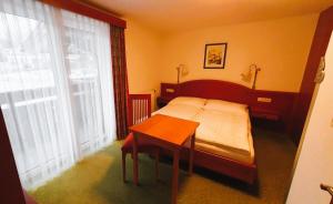 um quarto com uma cama, uma mesa e uma janela em Frühstückspension Seeblick em Sankt Gilgen