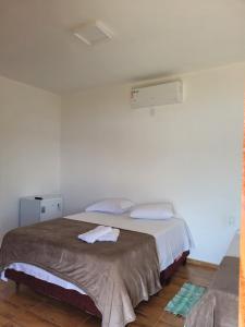 um quarto com uma cama grande e paredes brancas em Chalé Praia Vermelha 1 em Delfinópolis