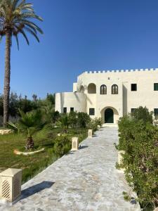 a building with a palm tree and a walkway at Dar Oueghlani - Maison d'hôtes in El Mây