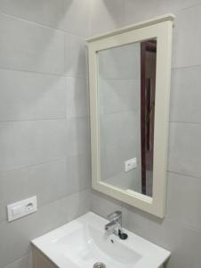 ein weißes Badezimmer mit einem Waschbecken und einem Spiegel in der Unterkunft LA RAZÓN DE MI SER in Chiclana de la Frontera