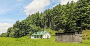 a small white house with a green roof in a field at Country Classic in Crumpler