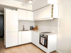 a white kitchen with white cabinets and a stove at Mai 71 Johanna suvekorter in Pärnu +13 photos