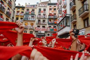 uma multidão de pessoas a levantar bandeiras vermelhas em Running of the Bulls All inclusive Camping Pamplona em Pamplona