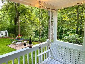 - une terrasse couverte blanche avec une balançoire et une table dans l'établissement Cozy Cottage - New Rental 2023, à Lansing