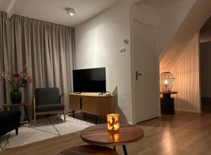 een woonkamer met een televisie en een tafel bij De Lijster in Bergen